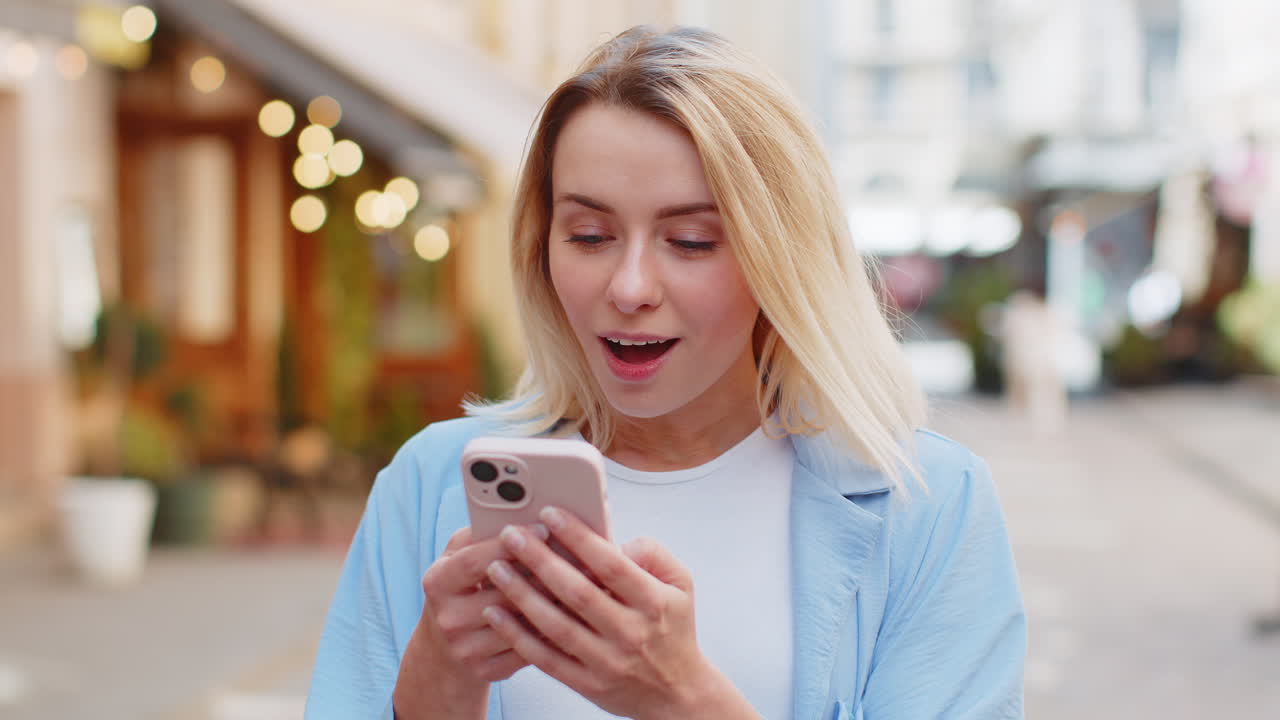 Eccitata felice vincitrice donna usa smartphone guardando lo schermo stupita festeggiando la vittoria buone notizie di messaggio