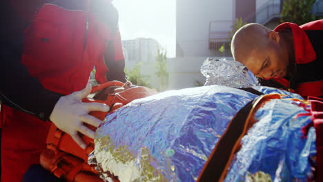 paramedics tying belt over the girl lying on stretcher