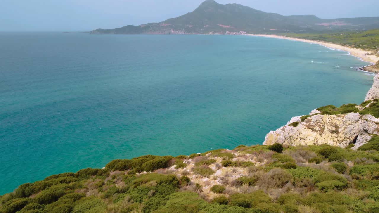 Baia sabbiosa con spiaggia naturale e costa rocciosa, sull'isola turistica della Sardegna, Italia, con montagne, sole e acqua limpida, azzurra, turchese e calma vicino a Costa Rei