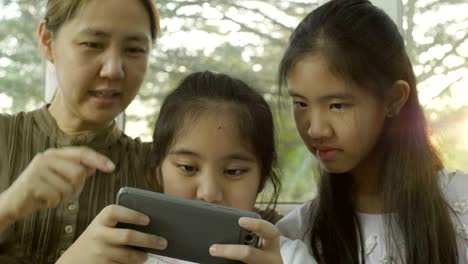 4k asian daughters playing games on smart phone with mother, happy time together