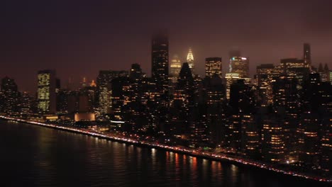 aerial pan across legendary new york city skyline at foggy twilight