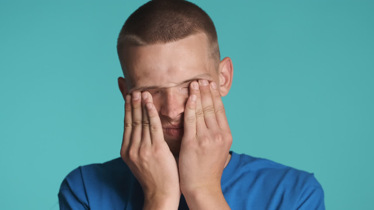 금발 남자가 눈을 문지르고