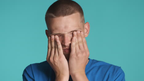 blond man rubbing his eyes