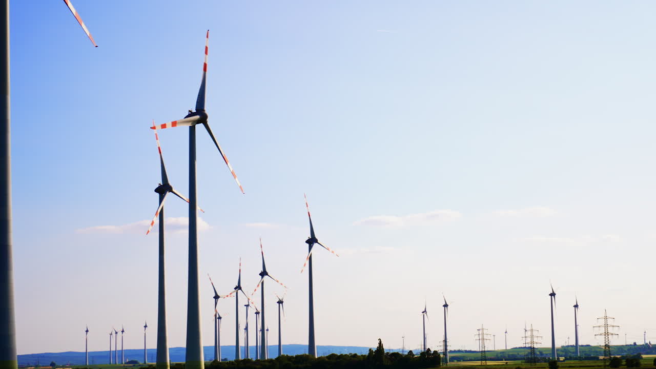 Turbines making clean energy. Rows of wind turbines spin against a clear blue sky, showcasing renewable energy production in a rural landscape
