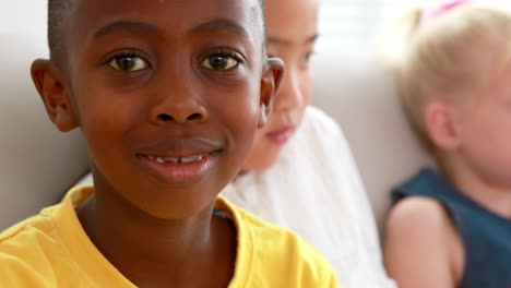 Tres-Lindos-Niños-En-El-Sofá-Con-Un-Niño-Sonriendo-A-La-Cámara