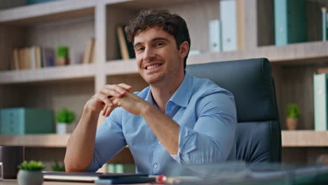 Portrait successful executive posing at office desk. Smiling brunette man look