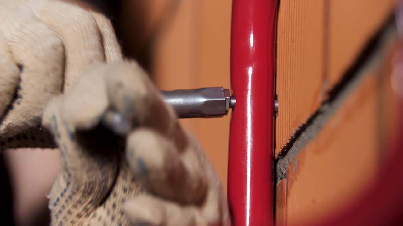 la instalación de una barandilla de metal rojo en la pared de ladrillo