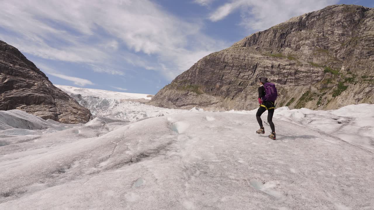 Hiker crossing glacier in Norway, dramatic landscape, adventure and solitude vibes