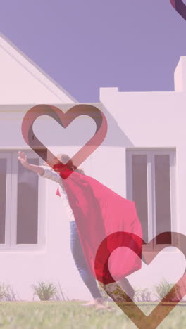 animation of hearts falling over caucasian woman and her son playing together in garden