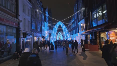 busy london street at night decorated for christmas ignoring covid restrictions groups gathering