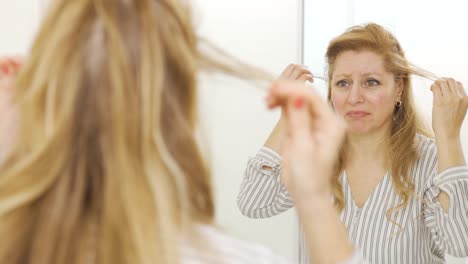 Reife-Frau,-Die-Ihr-Fallendes-Haar-Betrachtet.-Haarausfall.