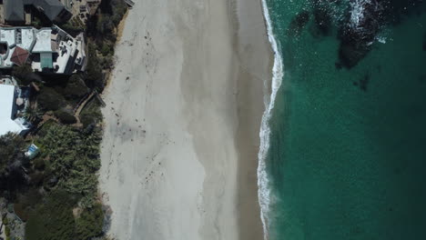 Drone-shot-looking-down-on-the-white-sand-in-Laguna-Beach,-California