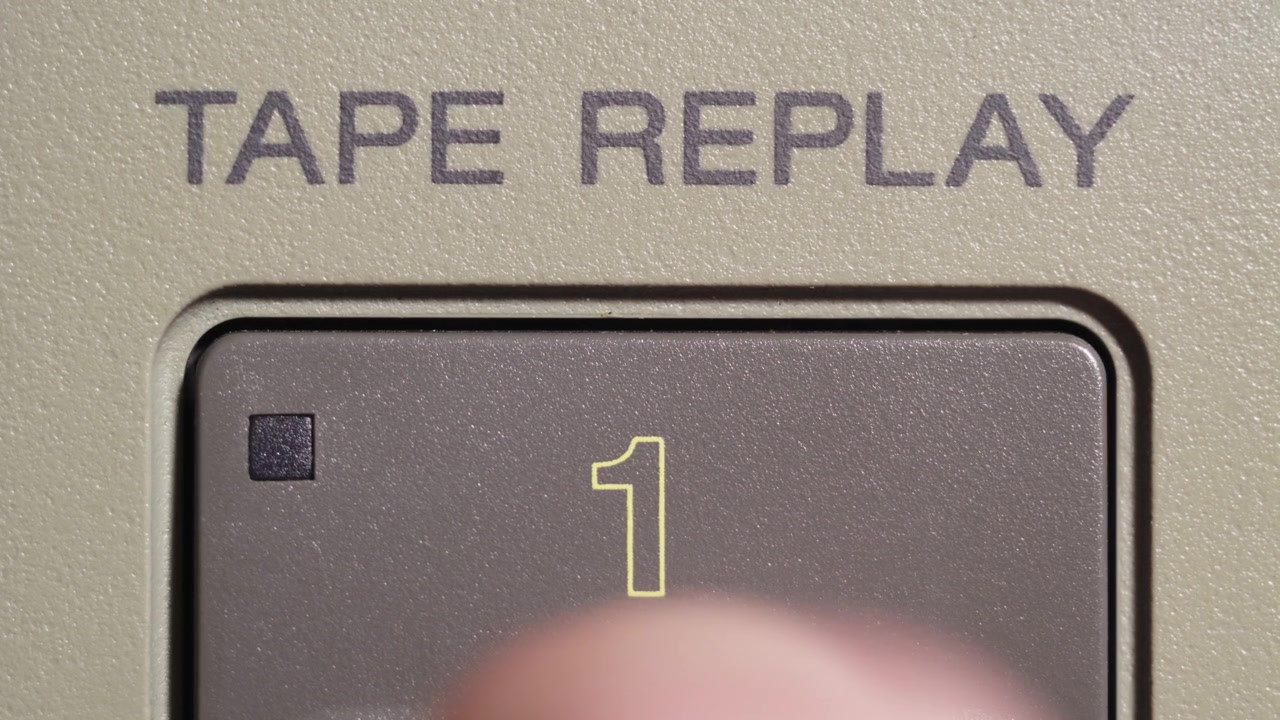 Finger presses tape replay button marked 1 on vintage editing remote controller