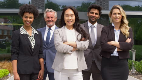 portrait of smiling multi-cultural business team outside modern office building