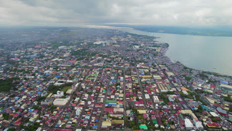 aerial drone view of urban city neighborhoods, buildings, and streets next to ocean coast in the philippines