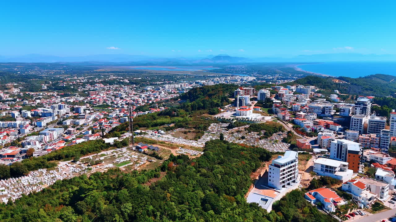 Elevando-se acima da montanha verde com infraestrutura urbana. Vasta paisagem urbana na costa do Mar Adriático, em Montenegro. Vista aérea