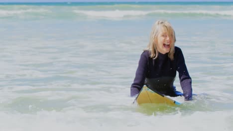 front view of active senior caucasian female surfer surfing on sea in the sunshine 4k