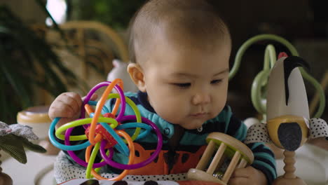 cute mixed race asian baby playing and banging his rattle toys and keeping himself busy and amused