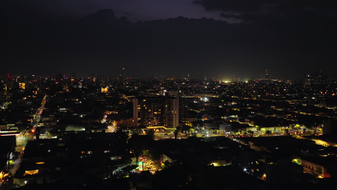 Drone video showcasing Guadalajara's vibrant skyline at night, highlighting Torre Trimera amidst twinkling city lights under a deep night sky. Captivating aerial footage