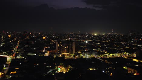 drone video showcasing guadalajara's vibrant skyline at night, highlighting torre trimera amidst twinkling city lights under a deep night sky. captivating aerial footage