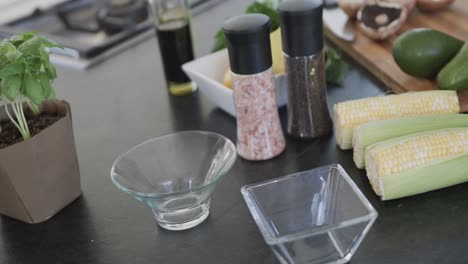 Close-up-of-countertop-with-vegetables-and-seasoning-in-kitchen,-slow-motion