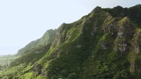 Drone-Shot-of-the-beautifully-dramatic-Kualoa-Mountain-Range-during-sunrise-hours-on-Oahu,-Hawaii