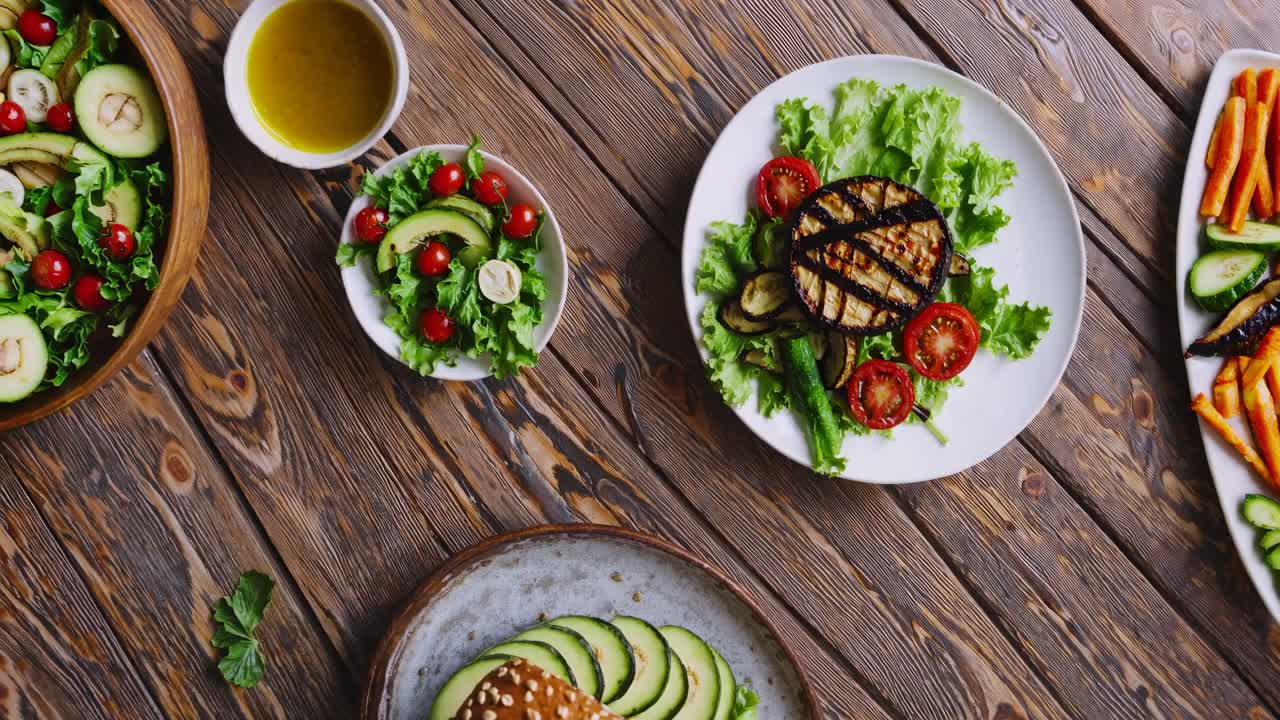 Top-down video shot of a rustic table with fresh salads and grilled vegetables