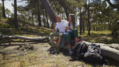 Young-couple-drinking-from-metal-cups-in-forest