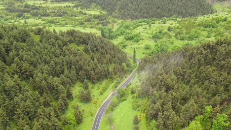 aerial drone view of a mountain road in the pyrenees leading into a beautiful valley