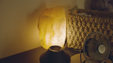 en una sala de masaje, una lámpara de piedra de sal iluminada se coloca de cerca, reflejando suavemente la luz en la habitación