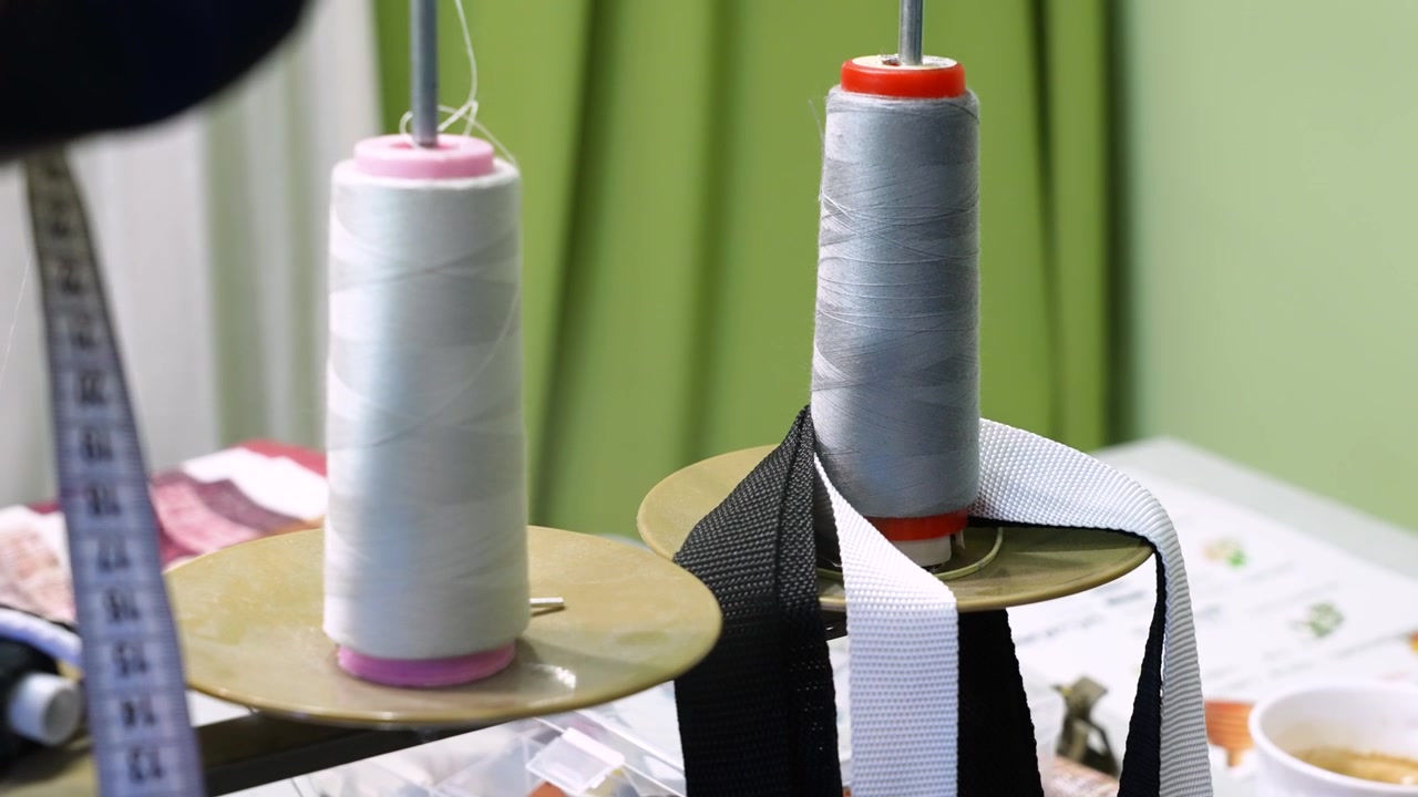 Professional sewing machine working with two spools of thread unwinding in a textile factory