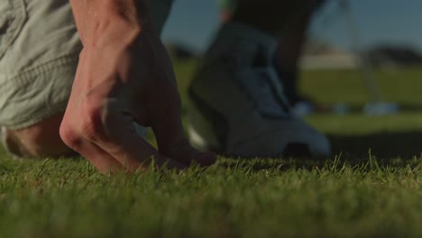 a golfer placing a tee on a golf course