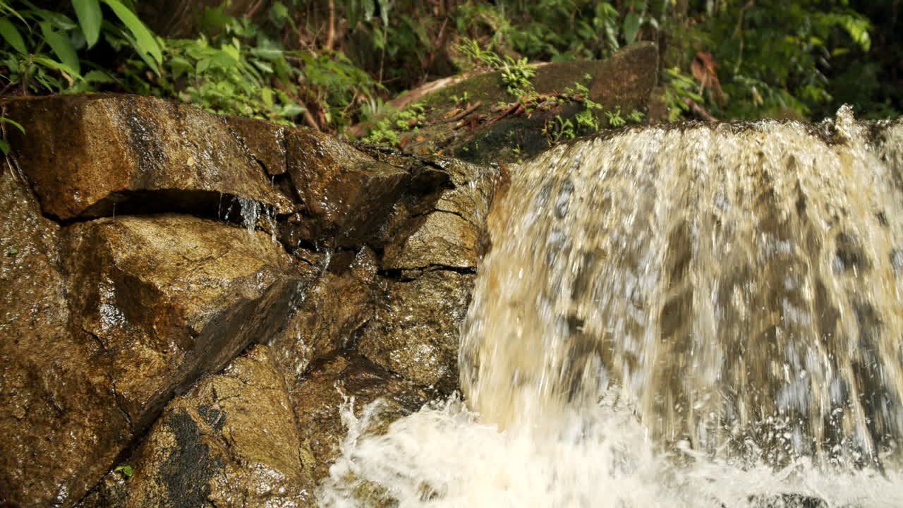 el agua naturalmente marrón y fangosa que cae en un escalón rocoso en las cataratas de bacara en guyana - de cerca