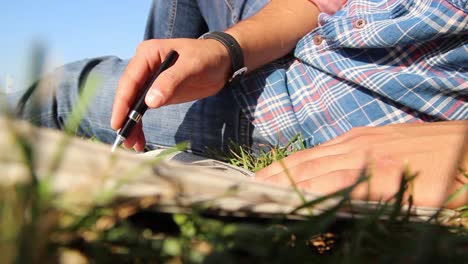 young man reading newspaper at park