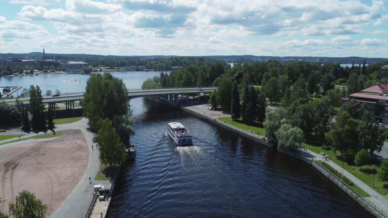 Tour boat of tourists motors in river canal in sunny Tampere Finland