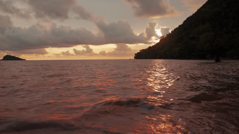 Gentle-ocean-waves-caress-the-lonely-beach-in-Koh-Chang,-Thailand,-while-the-sky-is-ablaze-with-the-warm-hues-of-a-breathtaking-sunset-–-a-vivid-canvas-of-yellow,-orange,-and-red