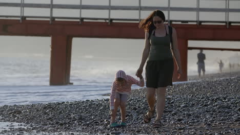 mother and son walk on the beach at sunset