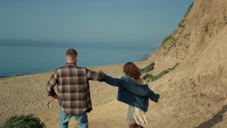 Beautiful-couple-holding-hands-walking-sea-shore.-Happy-lovers-hugging-kissing.