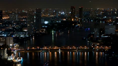 buildings and chao phraya river at night in bangkok city, thailand. 4k cityscape vdo