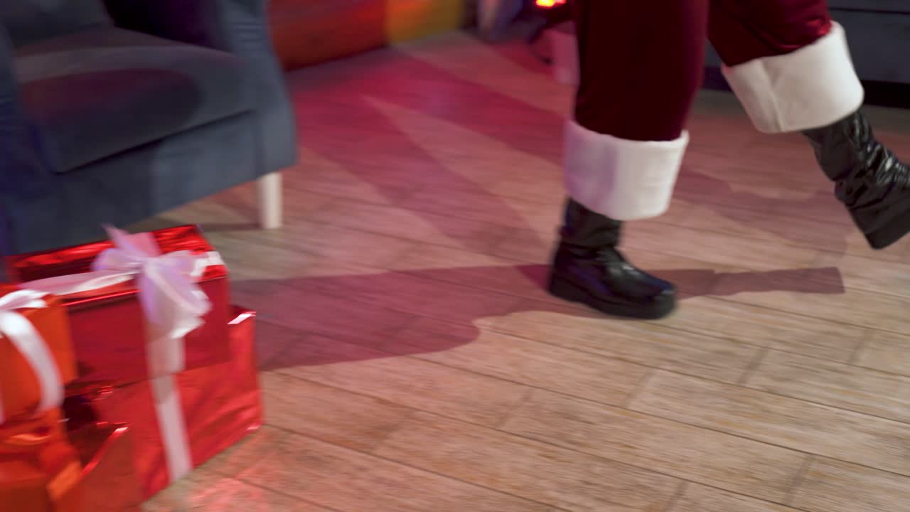 Santa Claus decorates the Christmas tree with toys in the house. The departing steps of Santa