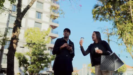 two people chatting and drinking coffee on a city street