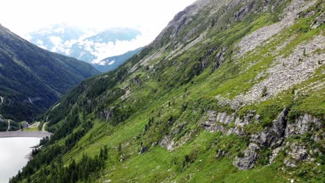 Steep-mountain-with-a-few-cliffs-next-to-an-artificial-lake-in-the-Alps-in-Kaernten,-Austria