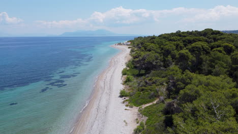 a beautiful shot of the greek coast where the trees, beach, and ocean meet