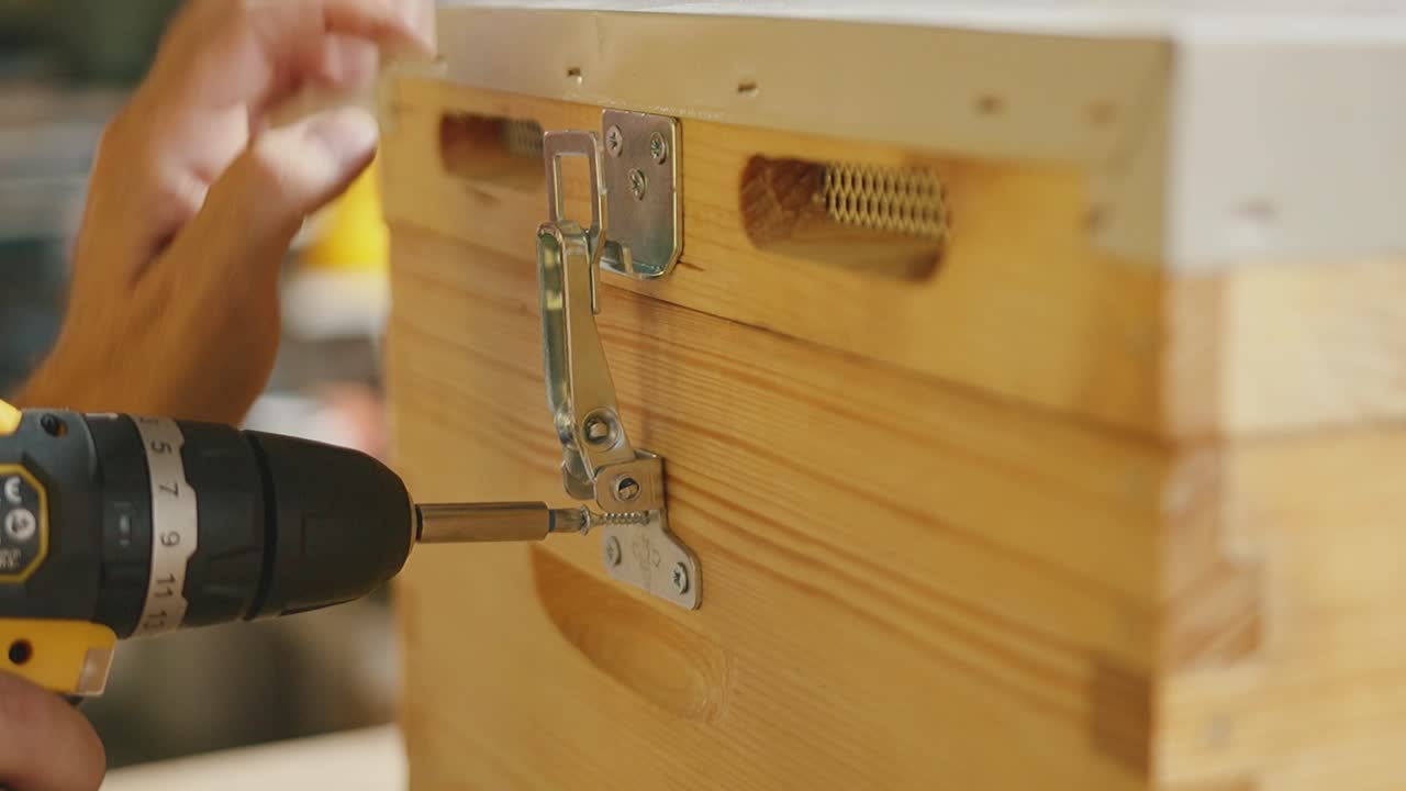 Hand screwing metal lock on wooden surface, close-up footage