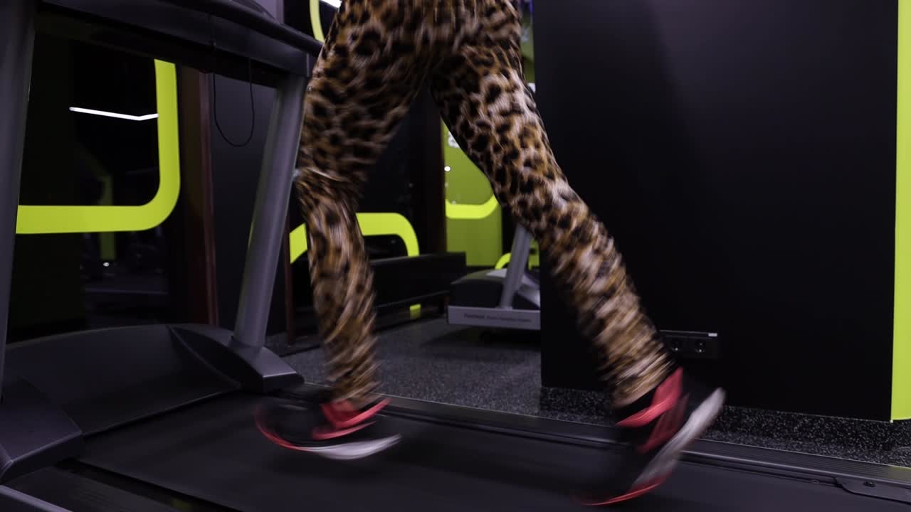 Slow motion shot of a fit young woman running on a treadmill at a gym