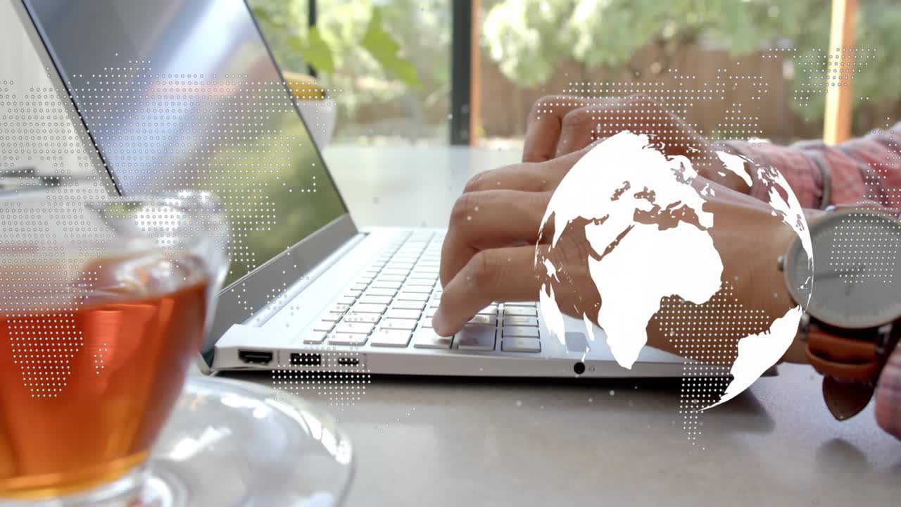 Man typing on laptop by window, keystrokes starting tech globe drifting over keys for work