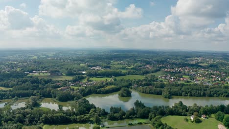 aerial drone shot of a lakes by the forests, fields and villages during summer
