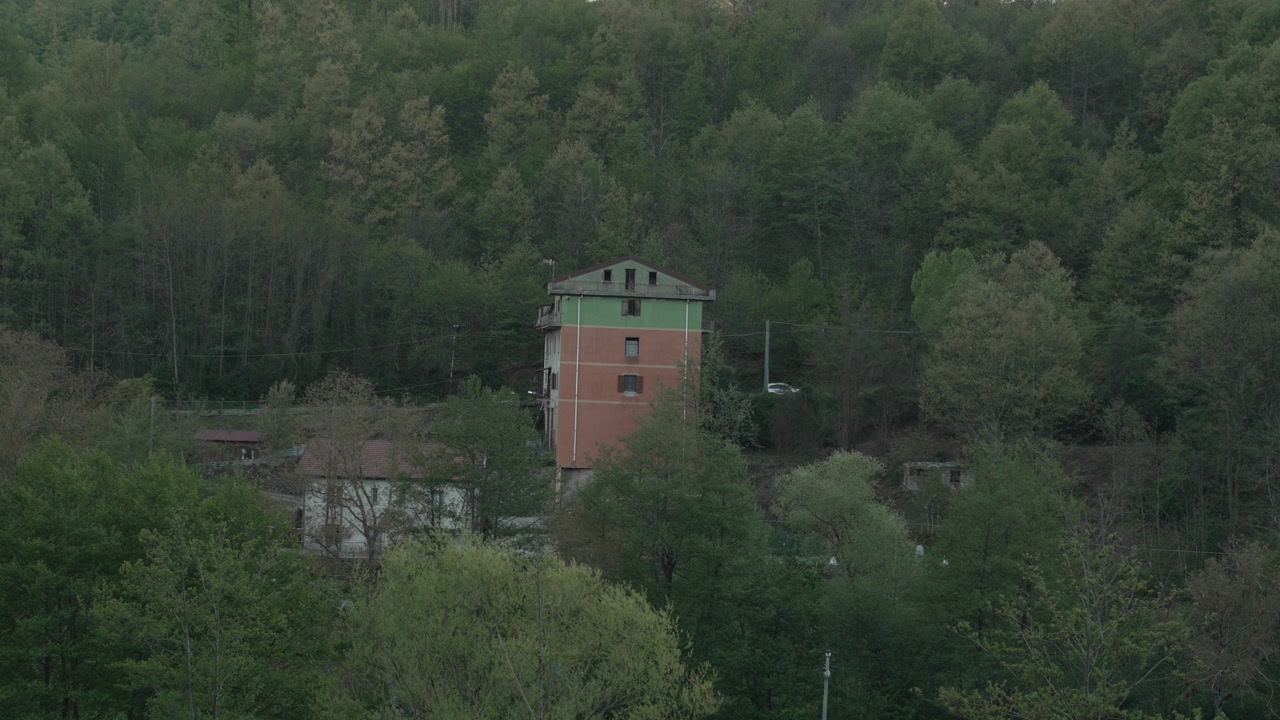 Ampia inquadratura panoramica di una casa isolata, alta e a più piani, nascosta e circondata da una fitta e lussureggiante foresta verde sui monti Appennini della Calabria, Italia meridionale