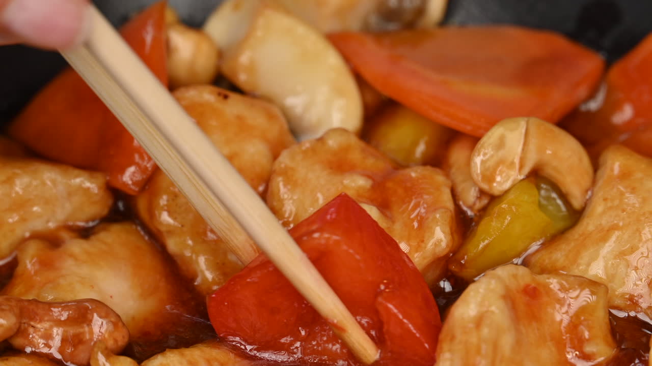 Woman eating chicken with vegetables and sweet sauce in a black pan at a chinese restaurant
