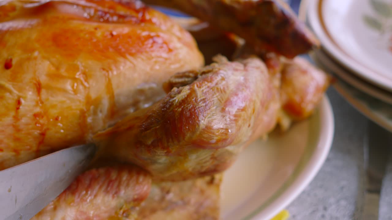 Turkey Leg Being Carved with Sharp Knife to Serve on Plate for Guests to Eat. Traditional Dinner Christmas or Thanksgiving Food.